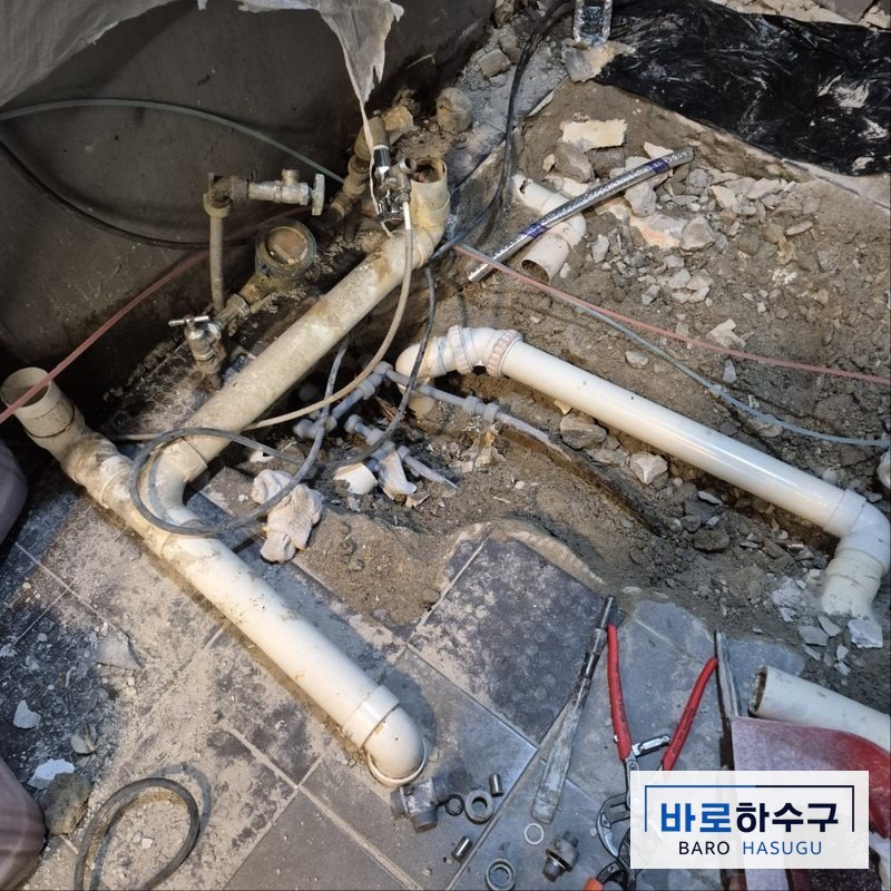 바닥을 열고 주철관 대신 새로 설치한 흰색 PVC 가지 배관