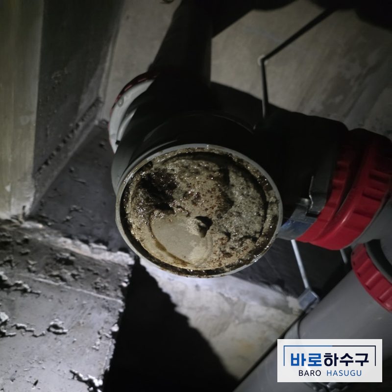 분리한 욕실 배관 단면에 굳은 시멘트가 가득 차 통로가 막혀 있는 작업 전 상태